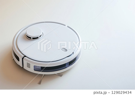 White robot vacuum cleaner standing on a white floor, ready to clean a modern home 129029434