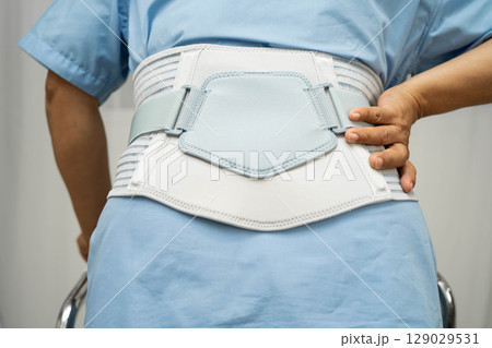 Asian senior pain back wearing elastic support belt with walker. 129029531