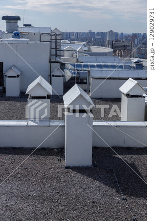A Captivating Rooftop View: Unique Chimneys and Modern Urban Skyline in the Background Under Clear Skies with Light Clouds 129029731