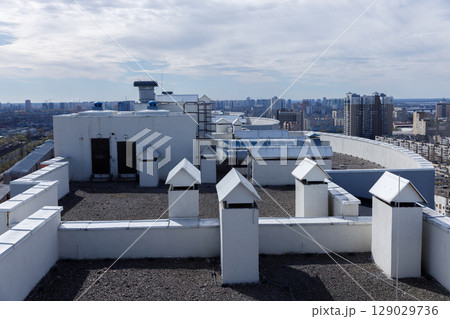Overview of a Rooftop Featuring Ventilation Structures and Urban Landscape in a Modern Cityscape Under a Clear Sky Overview of a Rooftop Featuring Ventilation Structures and Urban Landscape in a Modern Cityscape Under a Clear Sky 129029736