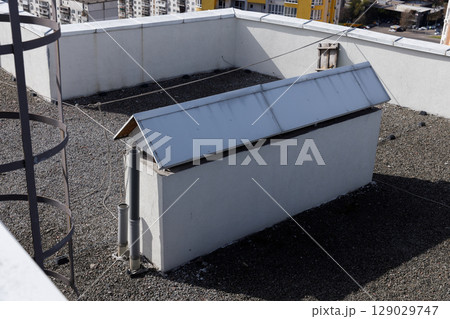 A View of a Rooftop Featuring a White Structure with a Metal Roof, Surveillance Features, and Surrounding Gravel in an Urban Environment 129029747