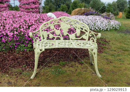 A Charming Decorative Bench Surrounded by Vibrant Flowerbeds in Blooming Colors, Perfect for Relaxation and Enjoyment of Nature's Beauty A Charming Decorative Bench Surrounded by Vibrant Flowerbeds in Blooming Colors, Perfect for Relaxation and Enjoyment of Nature's Beauty 129029913