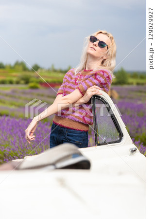 A Stunning Model Poses Elegantly Among Vibrant Lavender Fields in a Stylish Knit Sweater and Sunglasses, Creating an Artistic Visual Delight A Stunning Model Poses Elegantly Among Vibrant Lavender Fields in a Stylish Knit Sweater and Sunglasses, Creating an Artistic Visual Delight 129029927