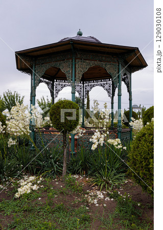 A Beautifully Designed Gazebo Surrounded by Lush Greenery and White Flowers, Perfect for Relaxation and Enjoying Nature's Serenity in a Garden Setting 129030108