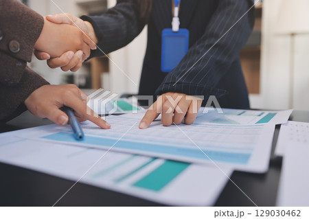 Business people shaking hands in office. Two business partners shaking hands after signing a contract in office. Business people shaking hands in office. Two business partners shaking hands after signing a contract in office. 129030462