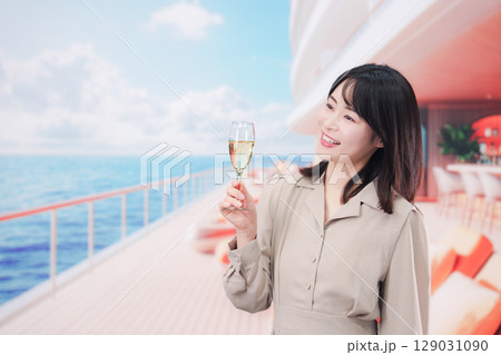 クルーズ船のデッキでスパークリングワインを飲む若い女性 129031090