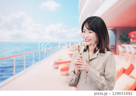 クルーズ船のデッキでスパークリングワインを飲む若い女性 129031092