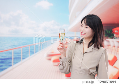 クルーズ船のデッキでスパークリングワインを飲む若い女性 129031094