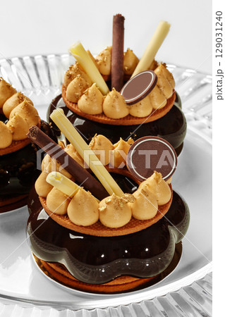 Delicious chocolate cakes decorated with gold and caramel cream filling glass serving dish 129031240