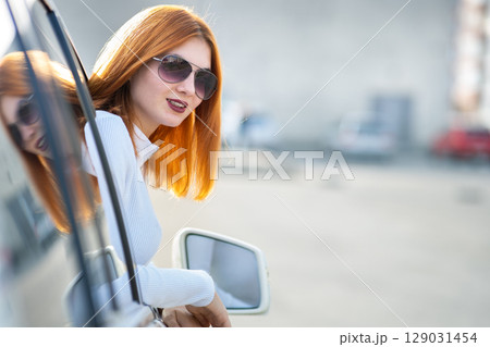 Young pretty woman driver in sunglasses looking out the car front window on a sunny summer day. Young pretty woman driver in sunglasses looking out the car front window on a sunny summer day. 129031454