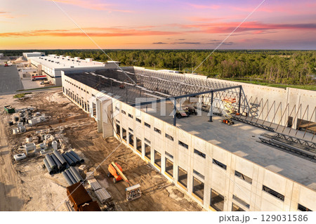 Warehouse construction. Concrete and metal structure of industrial building. Frame of modern logistic center Warehouse construction. Concrete and metal structure of industrial building. Frame of modern logistic center 129031586