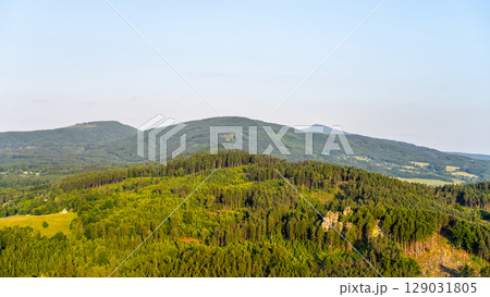 Witness the breathtaking sunset over Jested Ridge as viewed from the Popov Cliffs in the Lusatian Mountains, featuring lush green forests and striking sandstone formations during evening. 129031805