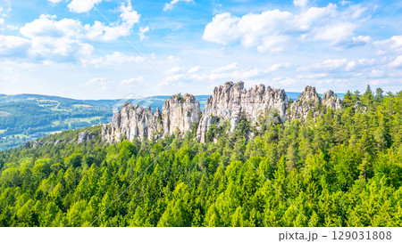 Breathtaking sandstone formations of Suche skaly tower above lush forests in the picturesque Bohemian Paradise of Czechia. Discover the natural beauty and geological wonders here. 129031808