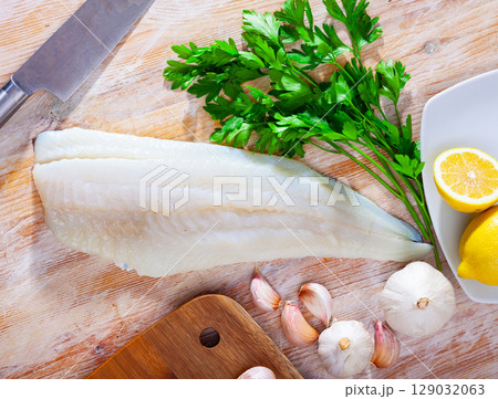 Raw cod fillet with garlic and lemon on wooden surface 129032063