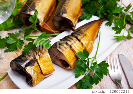 Smoked mackerel cut into pieces with parsley on a table Smoked mackerel cut into pieces with parsley on a table 129032212
