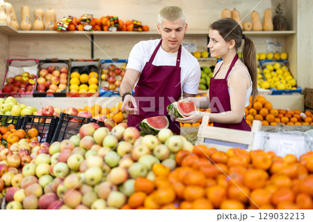 Two vendors lay out fruits and watermelons in a supermarket Two vendors lay out fruits and watermelons in a supermarket 129032213