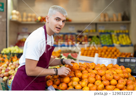 Guy shop seller puts tangerine goods on display case 129032227
