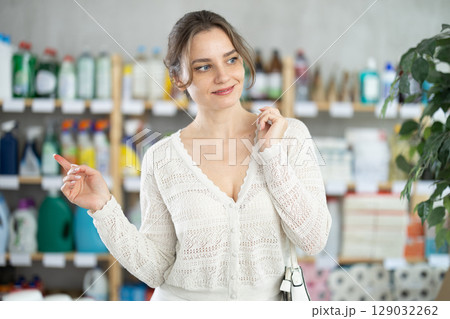 Woman wanders around store, looking at display cases Woman wanders around store, looking at display cases 129032262