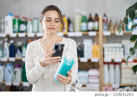 Woman client scans QR code on package and downloads promo code to purchase shampoo Woman client scans QR code on package and downloads promo code to purchase shampoo 129032263