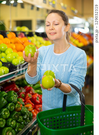 woman chooses apples in farm shop woman chooses apples in farm shop 129032319