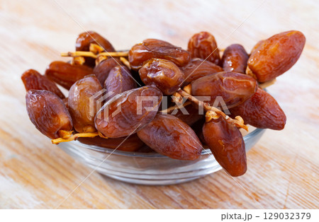 Sweet dried dates in plate on wooden table 129032379