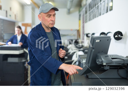 Printing house employee works on printing equipment Printing house employee works on printing equipment 129032396