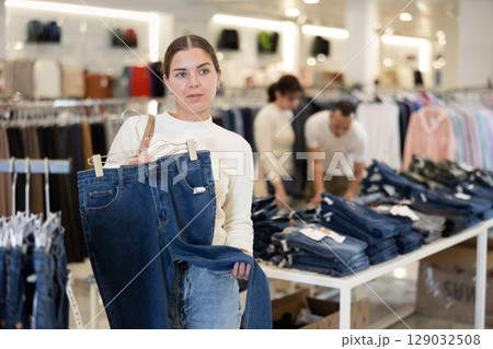 Young girl choosing blue jeans in clothing store 129032508