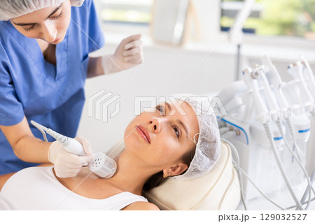 Young female cosmetologist performing neck whitening procedure on young woman Young female cosmetologist performing neck whitening procedure on young woman 129032527