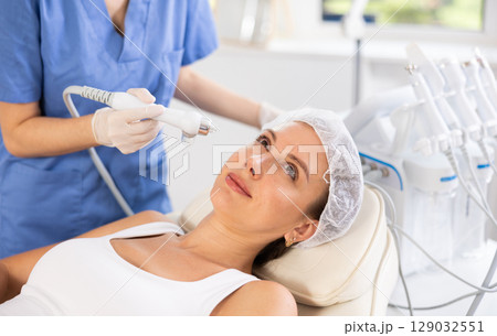 Young woman undergoing facial procedure using atomized cosmetic nutrients Young woman undergoing facial procedure using atomized cosmetic nutrients 129032551