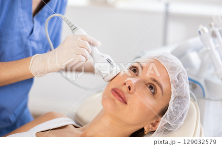 Young woman cosmetologist doing whitening procedure to young woman 129032579