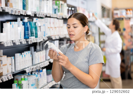Young woman chooses cosmetic product in pharmacy Young woman chooses cosmetic product in pharmacy 129032602