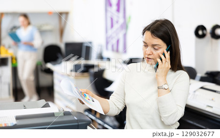 Woman printing office worker talking on phone Woman printing office worker talking on phone 129032677