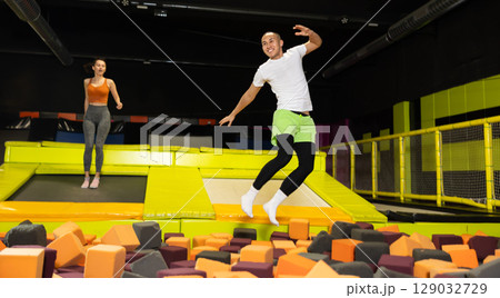 Young man playfully diving into foam cube pit at trampoline park 129032729