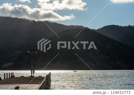 逆光に輝く冬の芦ノ湖。湖畔の桟橋とキラキラ光る水面の風景。 129032773