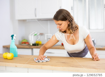 Focused young girl housewife cleaning table Focused young girl housewife cleaning table 129032785