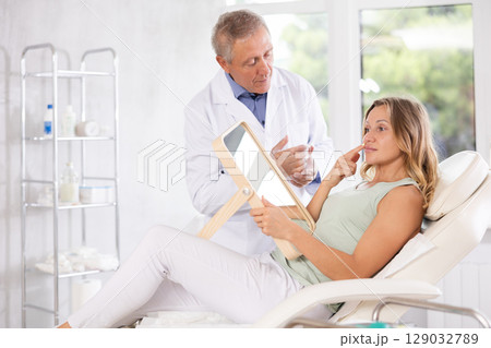 Elderly man doctor examining adult woman patient Elderly man doctor examining adult woman patient 129032789