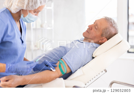 Woman doctor makes injection in arm of man 129032803