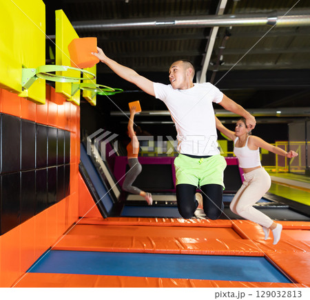 Cheerful man playing basketball with foam cube at trampoline park 129032813