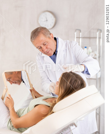 Senior man cosmetologist examines woman patients face after lifting procedure 129032851