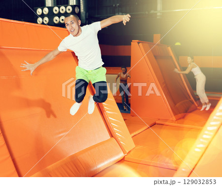Excited man pushing off from inclined surface in indoor trampoline center Excited man pushing off from inclined surface in indoor trampoline center 129032853