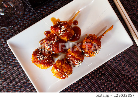 Appetizing balls of chicken with sesame seeds in spicy sauce. Japanese cuisine 129032857