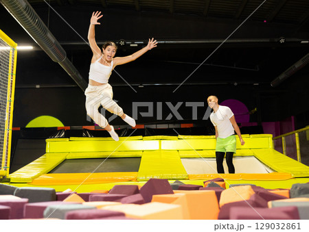 Happy athletes, man and girl, training to jump on trampolines at trampoline center 129032861