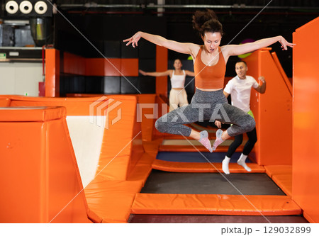 Middle-aged woman practice jumping on trampolines at trampoline center Middle-aged woman practice jumping on trampolines at trampoline center 129032899