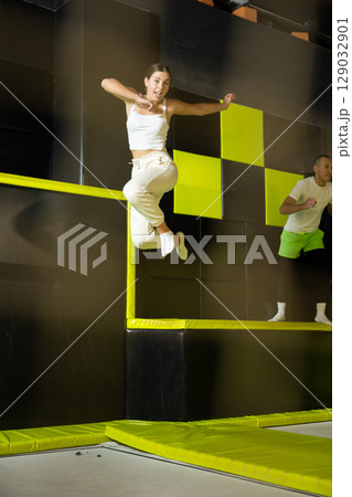 Happy girl bouncing on trampoline in indoor amusement park 129032901
