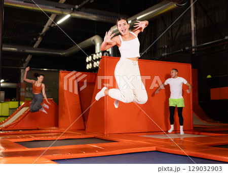 Excited young girl jumping at indoor trampoline center Excited young girl jumping at indoor trampoline center 129032903