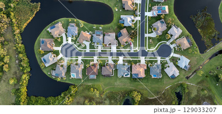 Upscale suburban homes with large backyards and green grassy lawns. Private residential houses in rural suburban sprawl area in Sarasota, Florida 129033207