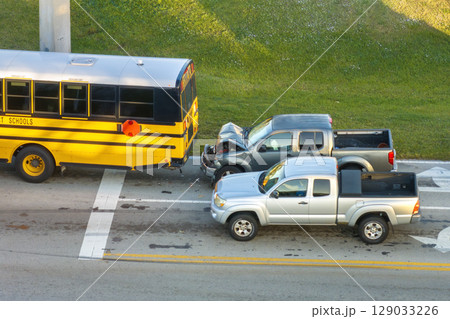 Traffic accident on American street in Florida. First responders helping victims of school bus and car crash on road in USA. Aerial view of emergency services responding to accident site Traffic accident on American street in Florida. First responders helping victims of school bus and car crash on road in USA. Aerial view of emergency services responding to accident site 129033226