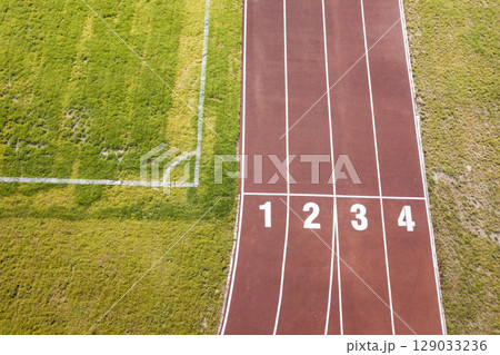 Top view of red running tracks and green grass lawn. Infrastructure for sports activities. 129033236
