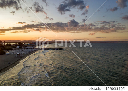 Sea surface with blue water waves under yellow and purple sunset sky. Sea surface with blue water waves under yellow and purple sunset sky. 129033395