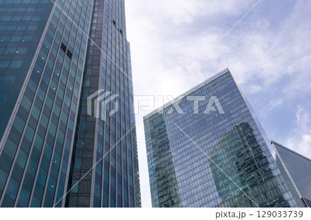 Low angle view of modern skyscrapers glass walls Low angle view of modern skyscrapers glass walls 129033739